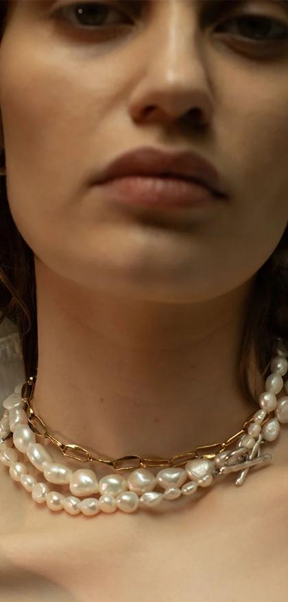 A close portrait of a model wearing a pearl choker
