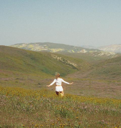 Woman running through a meadow of wildflowers in the hills