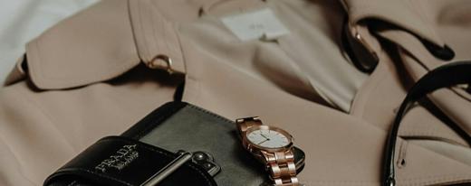 A close crop of a silk garment and a watch on a pale surface