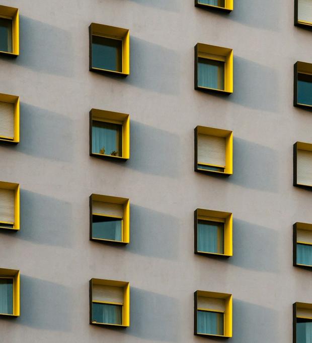 A building facade with rows of identical square windows, each framed in yellow