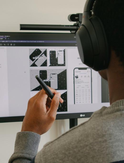A designer sketching wireframes on paper beside a laptop