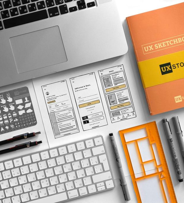 A desk with sketching pads, wireframe stencils and a keyboard