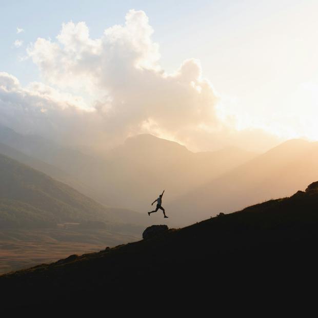 A runner leaping across a ridge at sunrise